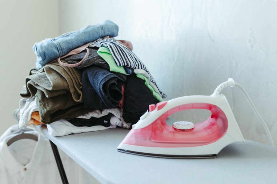 Iron and a stack of folded clothes on an ironing board